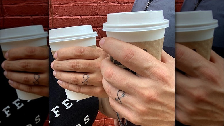couple wearing infinity ring finger tattoos