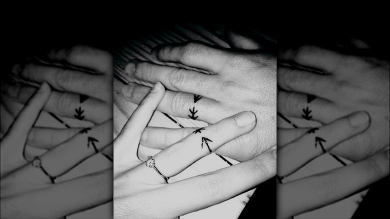couple with arrow ring finger tattoos
