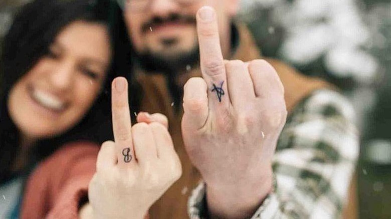couple wearing ring finger tattoos
