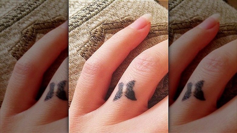 woman with butterfly ring finger tattoo