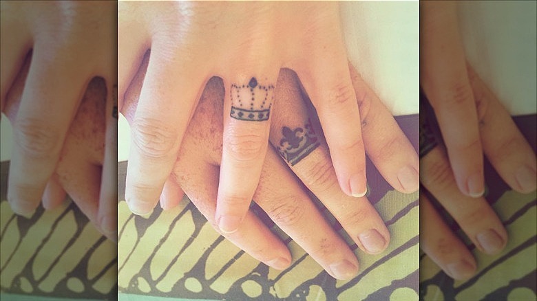 couple wearing crown wedding ring tattoos