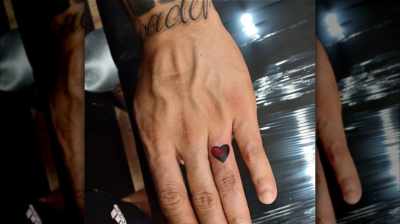 person wearing heart ring finger tattoo