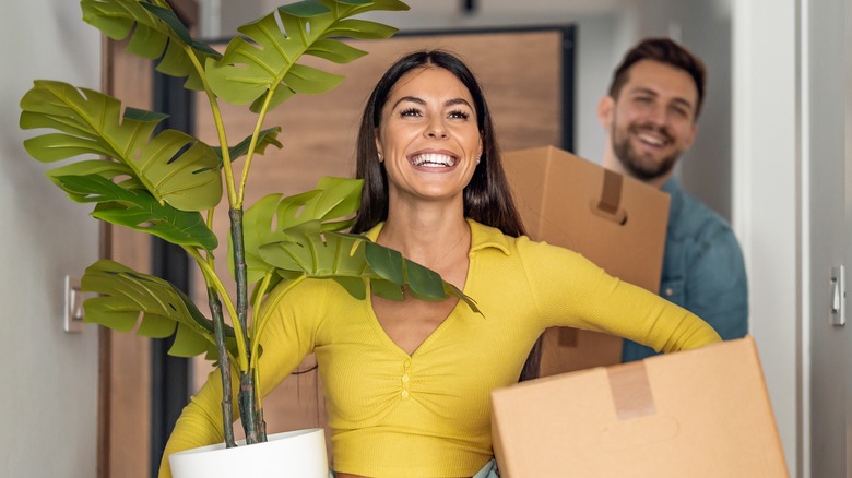 Smiling couple carrying moving boxes