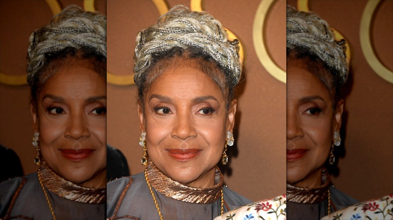 Phylicia Rashad smiles wearing gold jewellery and her hair in a braided bun