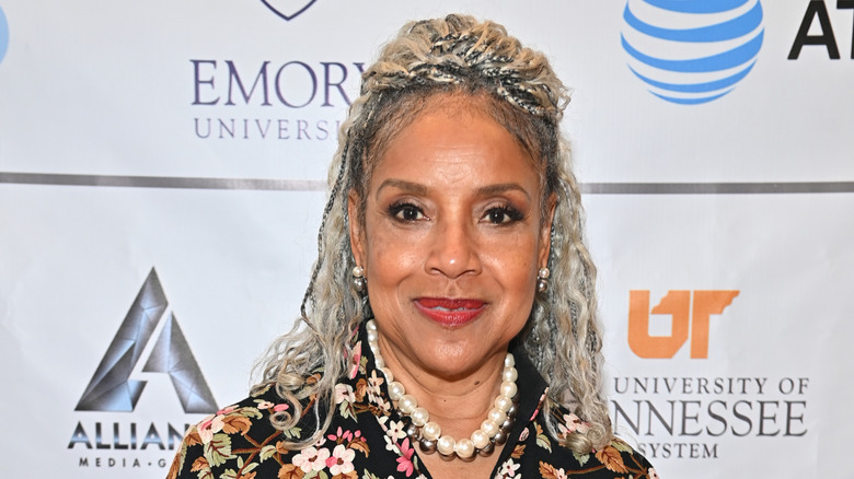 Phylicia Rashad smiles with silver braids wearing a floral dress
