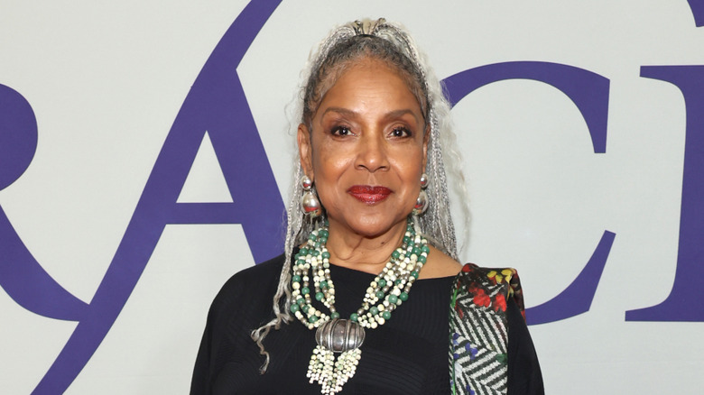 Phylicia Rashad smiles with silver braids wearing a statement beaded necklace