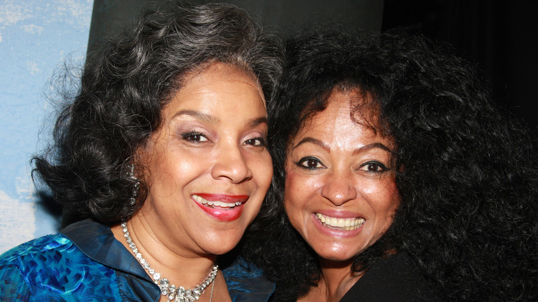 Phylicia Rashad smiles next to Diana Ross wearing a blue blouse