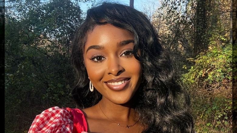 A darkskinned makeup maven with cottagecore makeup posing for a photo