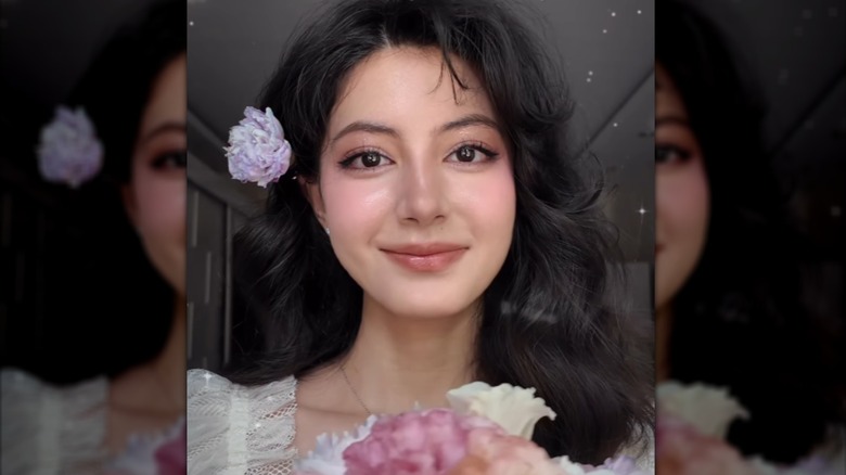 A person with a flower-inspired cottagecore makeup look smiling