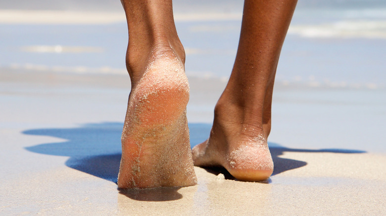 Black feet walking on sandy beach