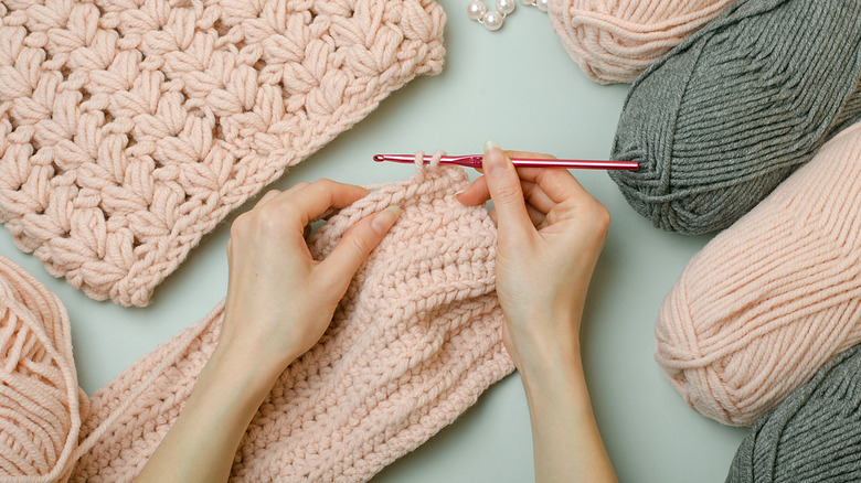 Person crocheting scarf with pink yarn