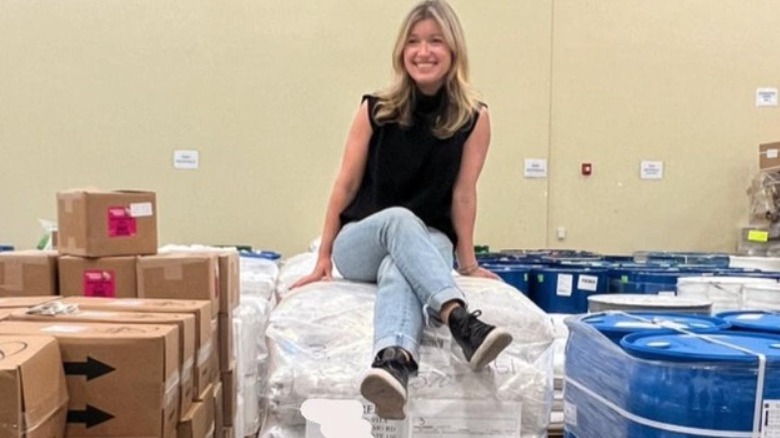 Sarah sitting on a stack of product