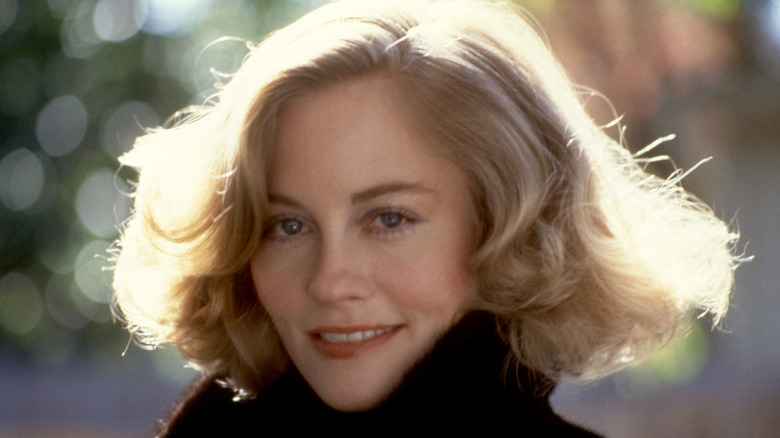 Cybill Shepherd smiling wearing a black coat with a voluminous bob.