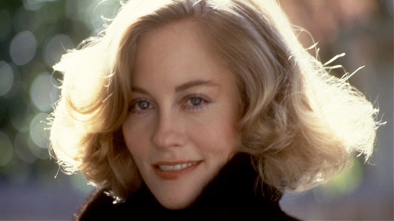 Cybill Shepherd smiling wearing a black coat with a voluminous bob.