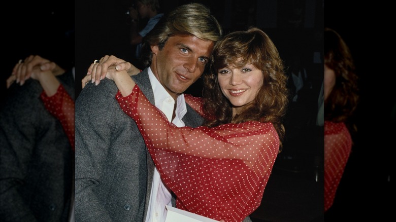 Victoria Principal wearing a sheer red-and-white polka dot top hugging Christopher Skinner circa 1979.