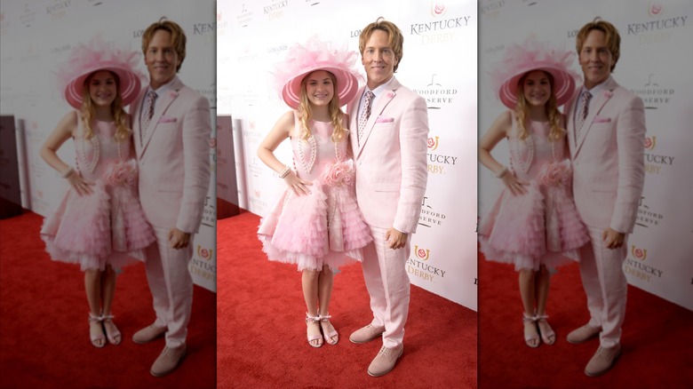 Dannielynn Birkhead stands next to Larry Birkhead wearing a pink dress and hat