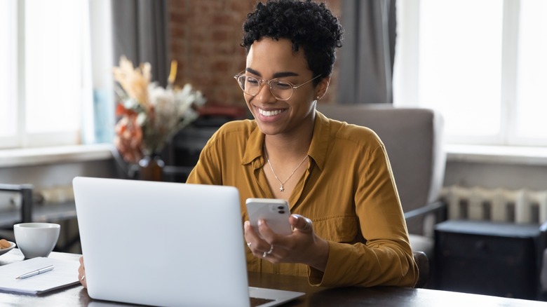 woman using phone and laptop