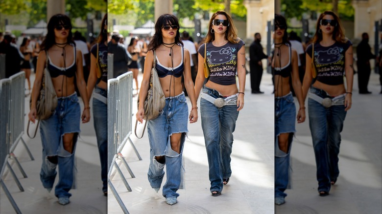 Two women walk down a Paris street. One of them is wearing heavily distressed jeans.