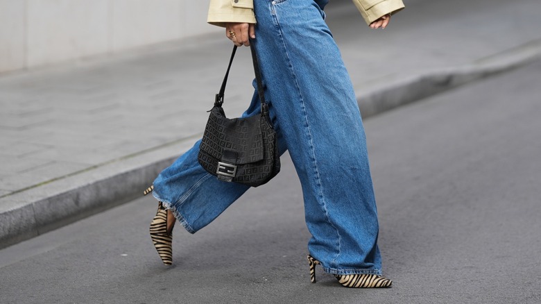 Photo of a woman from the waist down wearing wide-legged jeans and zebra print heels.