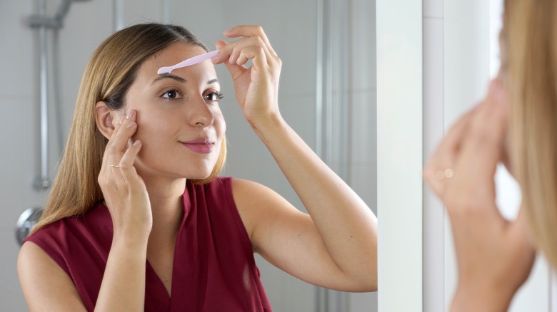woman using dermaplane razor on face