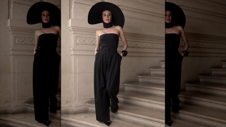 Diane Kruger wearing a strapless, black jumpsuit with a black choker and wide-brimmed black hat.