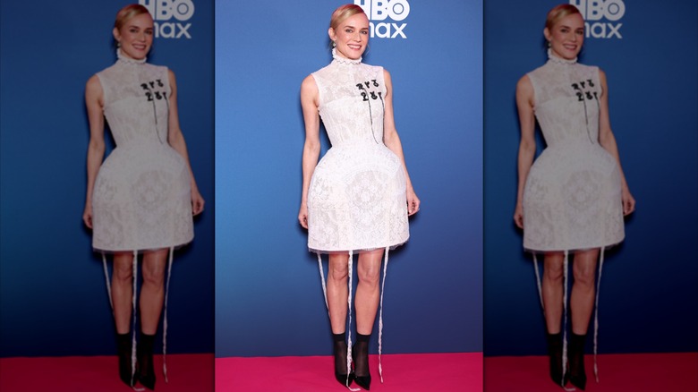 Diane Kruger on the red carpet wearing a short, white lace dress with black boots.