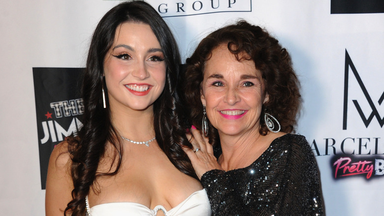 Olivia DeLaurentis in a white dress next to her mom Diane Franklin, wearing a sparkly black dress.