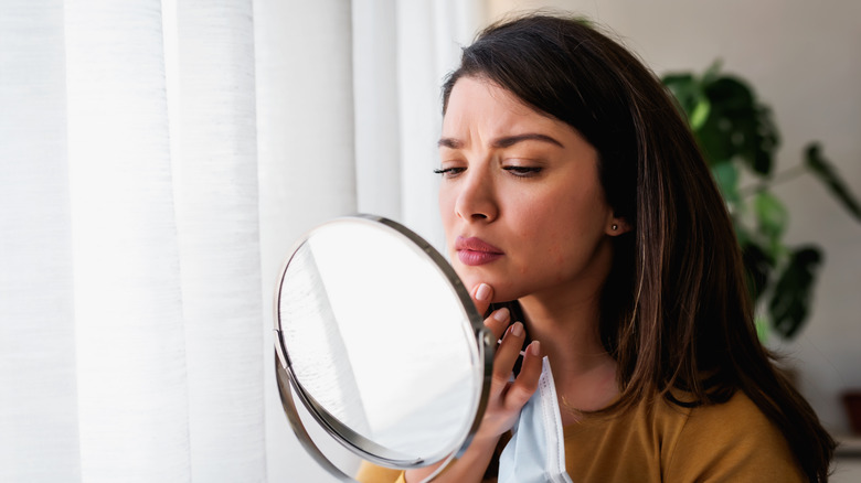 Concerned woman looking into mirror