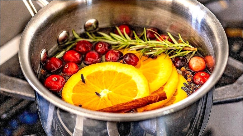 Saucepan simmering oranges, rosemary, cranberries, cinnamon