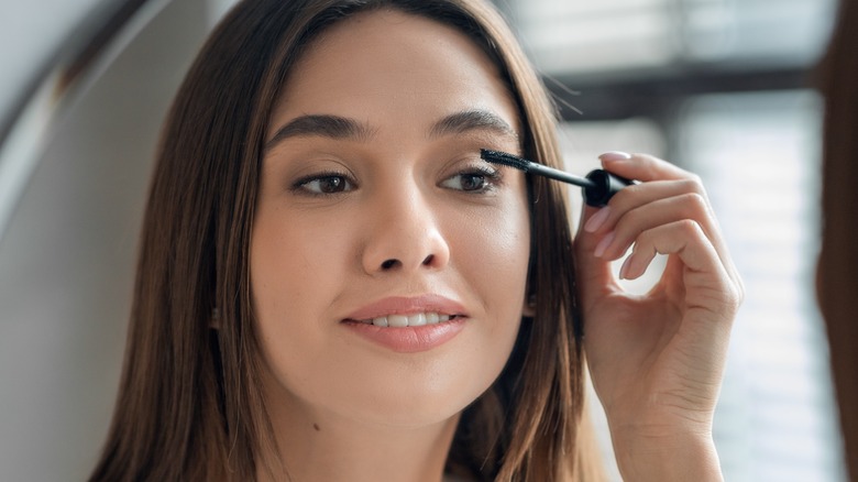 Smiling woman applying mascara 