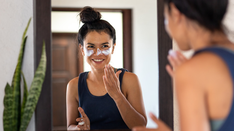 woman applying sunblock to face