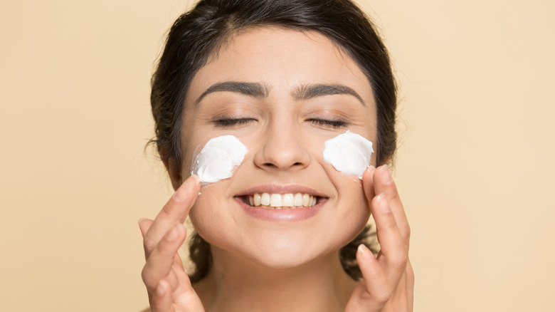 Woman applying skincare cream 