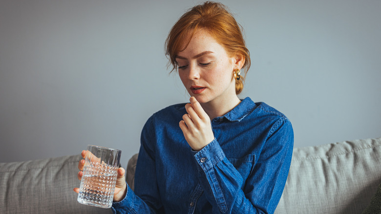 woman taking pill with water