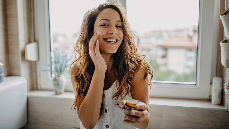 Smiling woman applying ghee cream