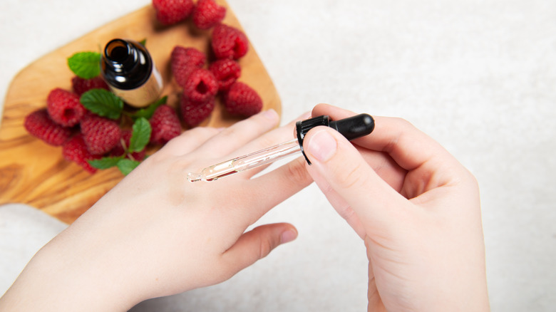 Closeup of woman applying raspberry seed oil to hand