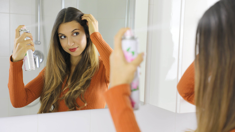 woman spraying product on hair