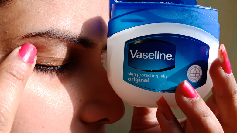 Woman applying vaseline on eye 