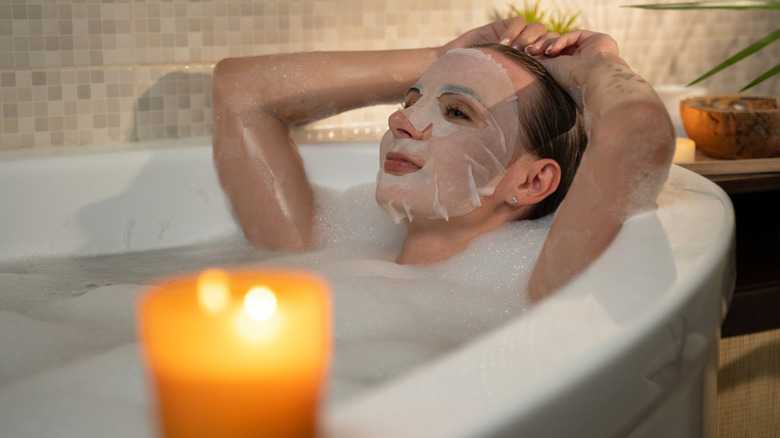A woman taking a bath while wearing a sheet mask.