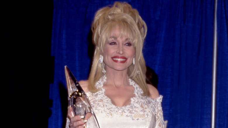 Dolly Parton smiling in a white look with red lipstick at the 1996 Country Music Awards