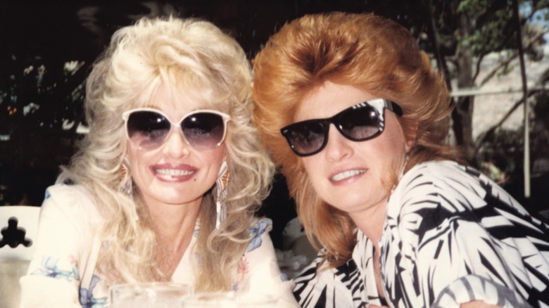 Dolly Parton (left) wearing sunglasses next to the redheaded Judy Ogle (right) also wearing sunglasses
