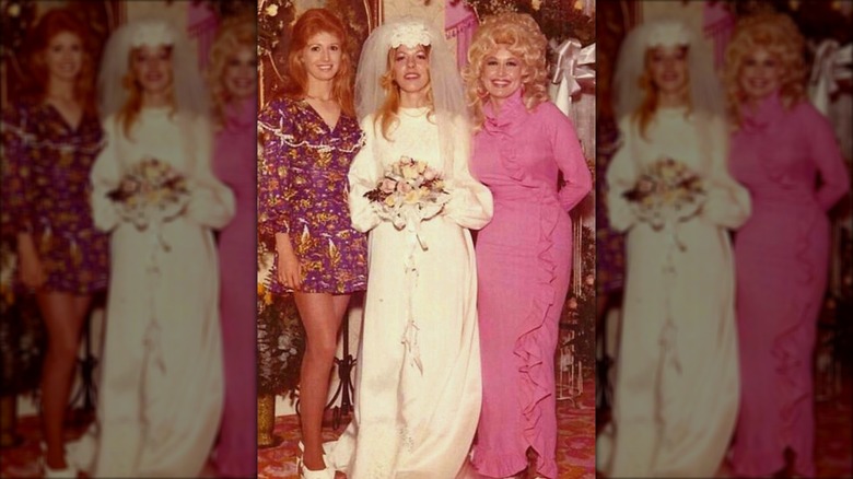 Judy Ogle (left) wearing a purple dress with long ginger hair next to Freida Parton (middle) and Dolly Parton (right)