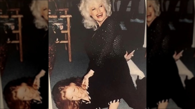 Judy Ogle lies under Dolly Parton wearing a black ensemble and her ginger hair splayed on the floor