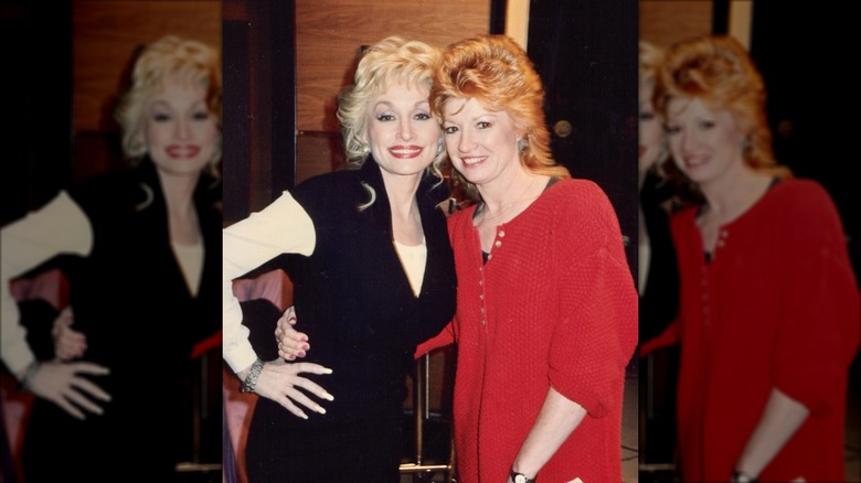 Dolly Parton (left) with Judy Ogle (right) wearing teased ginger hair and a red button-up dress