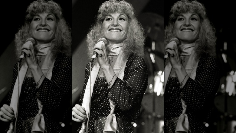 Stella Parton pictured in 1980 wearing a scarf and polka dot dress while singing