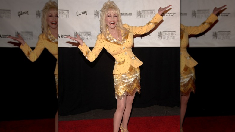 Dolly Parton on the red carpet in a yellow skirt suit