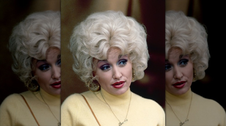 Dolly Parton wearing a blond bouffant wig and red lipstick