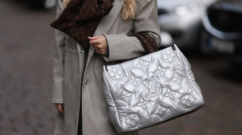 Girl carrying metallic Louis Vuitton puffer tote bag.