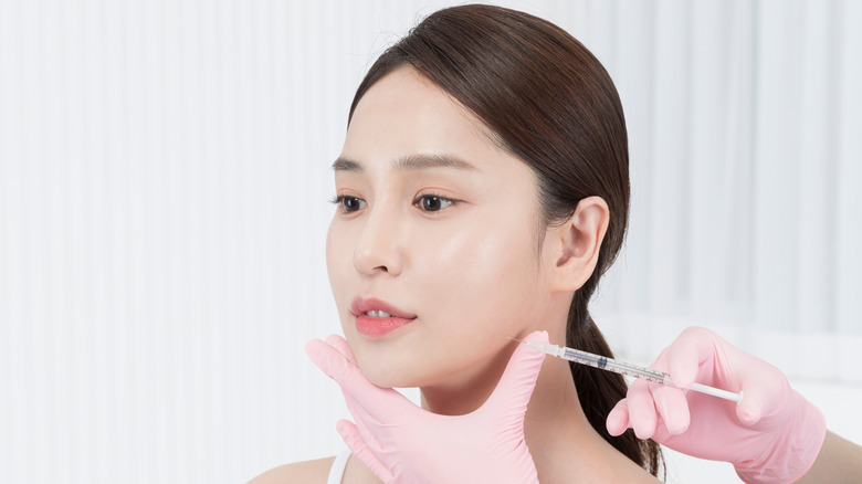 A woman getting a Botox injection along her jew