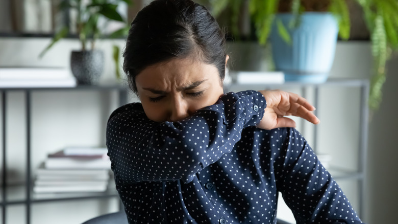 Girl sneezing into arm 