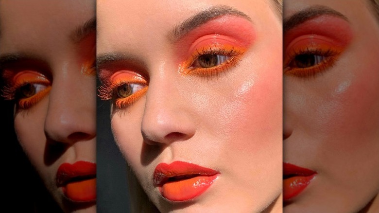 woman with orange eyeliner, pink eyeshadow, and orange lipstick
